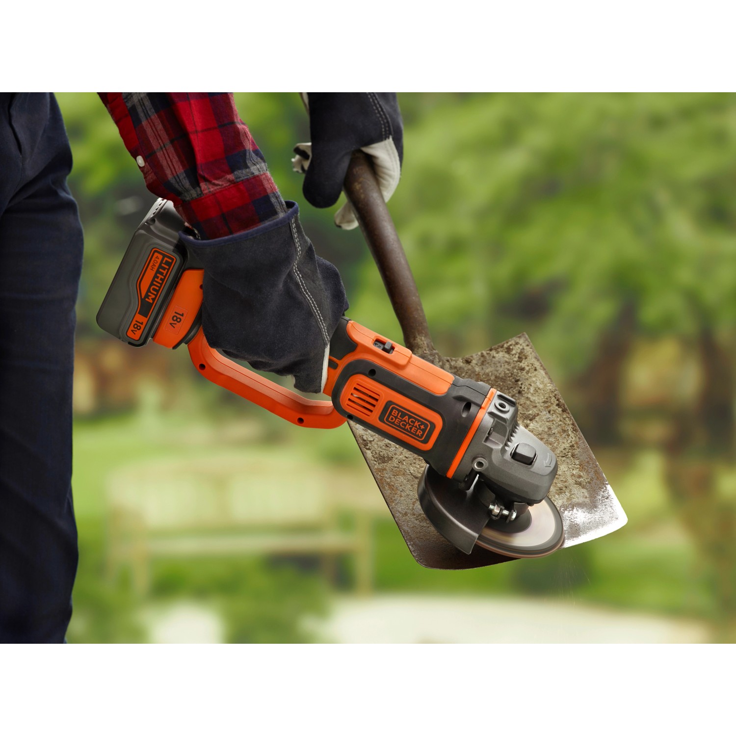 Smerigliatrice angolare a batteria Black+Decker 18V in uso, smerigliatura di una pala in giardino.