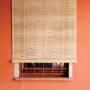 Tenda a rullo t.b.t. color naturale su finestra con parete arancione.