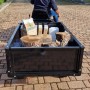 Rimorchio per trattorino tagliaerba carico di legna, fertilizzante e contenitore.