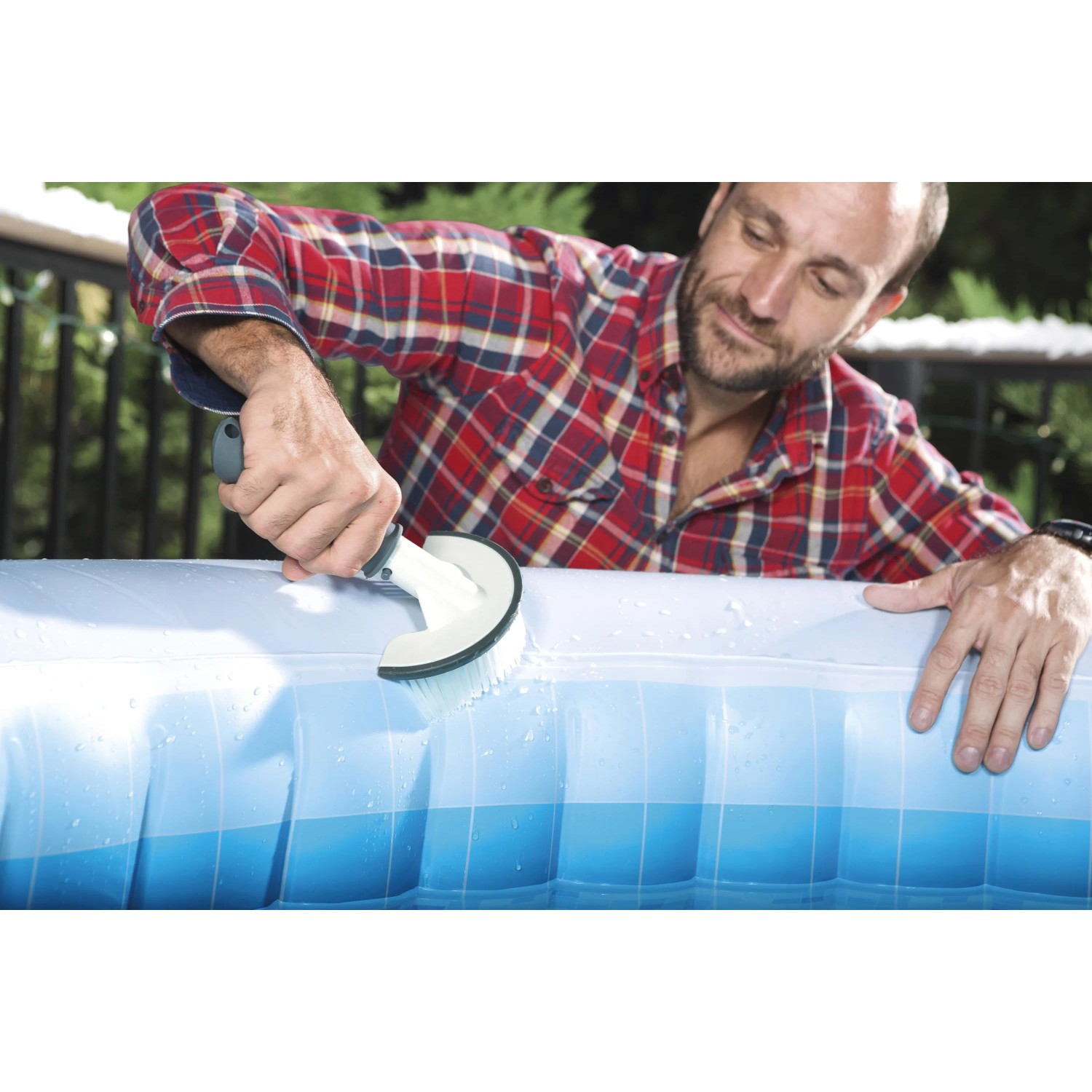 Uomo pulisce la piscina con una spazzola. Accessori per la cura e la pulizia della piscina.