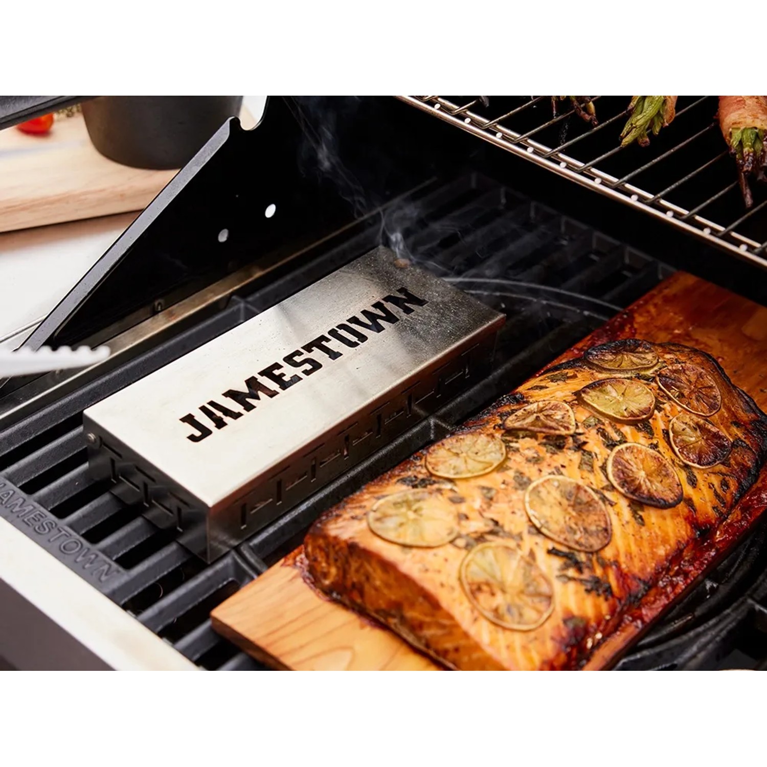 Affumicatore Jamestown in acciaio inox su griglia con salmone su tavola di legno. Accessorio grill per aroma affumicato.