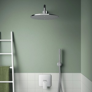 Set rubinetteria doccia con soffione e doccetta in cromo su parete verde.