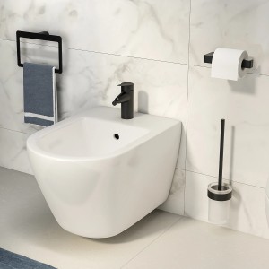 Bidet sospeso bianco con rubinetto nero e accessori in bagno.