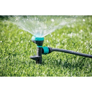 Irrigazione con irrigatori di superficie t.b.t. su prato, getto d'acqua visibile.
