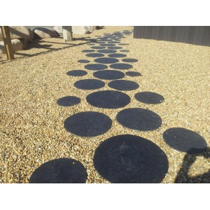 Sentiero di pietre circolari nere su ghiaia. Ciottoli e granulati.