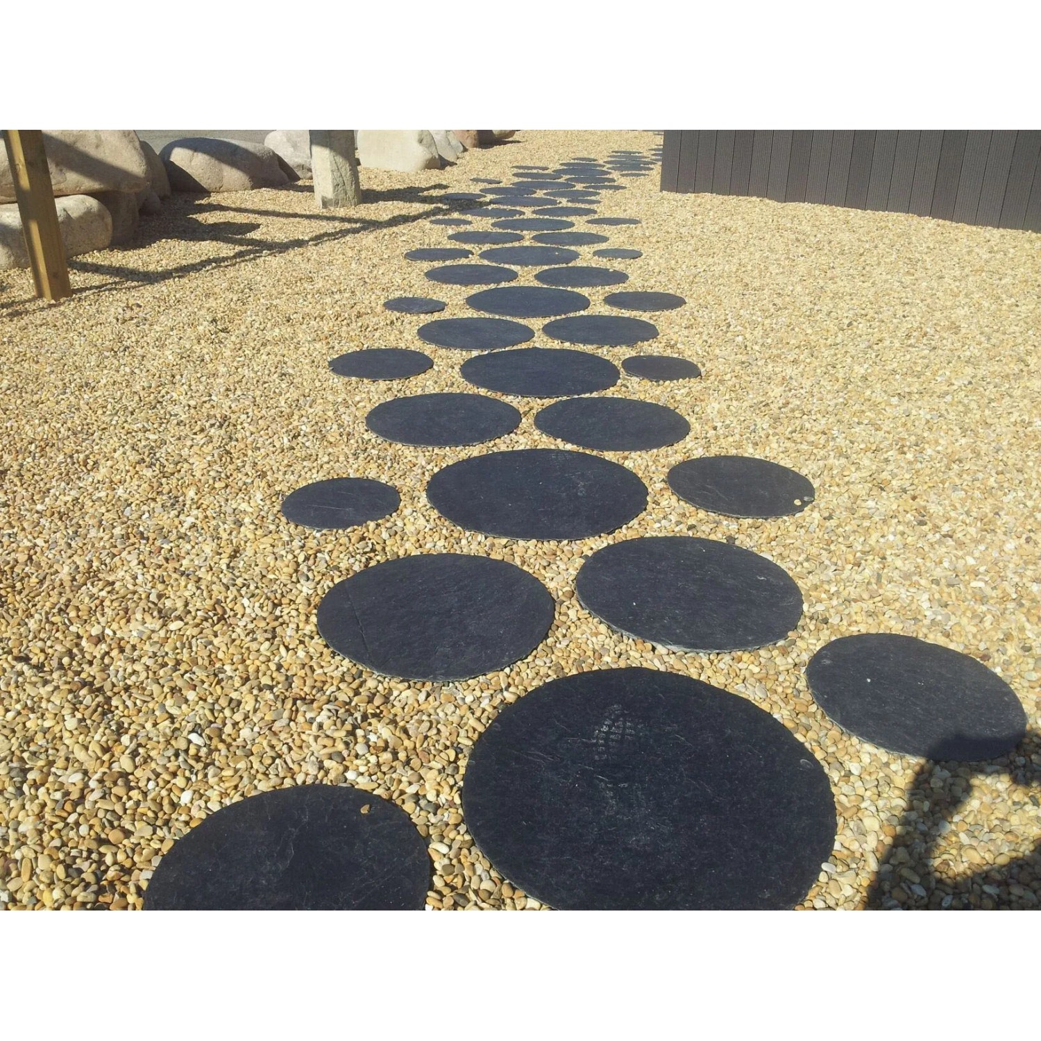 Sentiero di pietre circolari nere su ghiaia. Ciottoli e granulati.