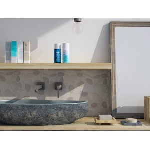 Piastrelle a mosaico in bagno con lavabo in pietra e prodotti per la cura su una mensola di legno.