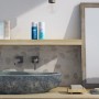 Piastrelle a mosaico in bagno con lavabo in pietra e prodotti per la cura su una mensola di legno.