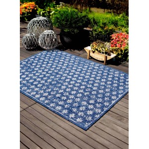 Tappeto da esterno blu con motivo floreale bianco su patio in legno.