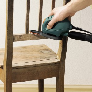 Levigatrice a mouse Black+Decker con set di cuscinetti abrasivi a dito LUX che leviga una sedia di legno.