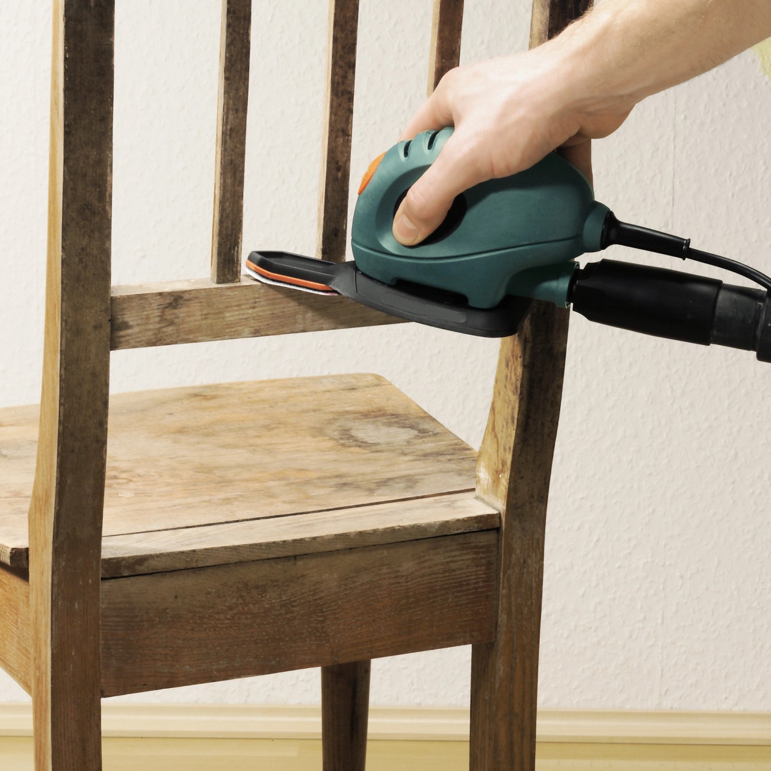 Levigatrice a mouse Black+Decker con set di cuscinetti abrasivi a dito LUX che leviga una sedia di legno.