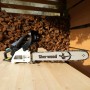Motosega t.b.t. su tavolo di legno davanti a catasta di legna.