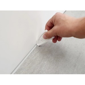 Mano che utilizza lo spatolatore universale per fughe tra parete e pavimento.