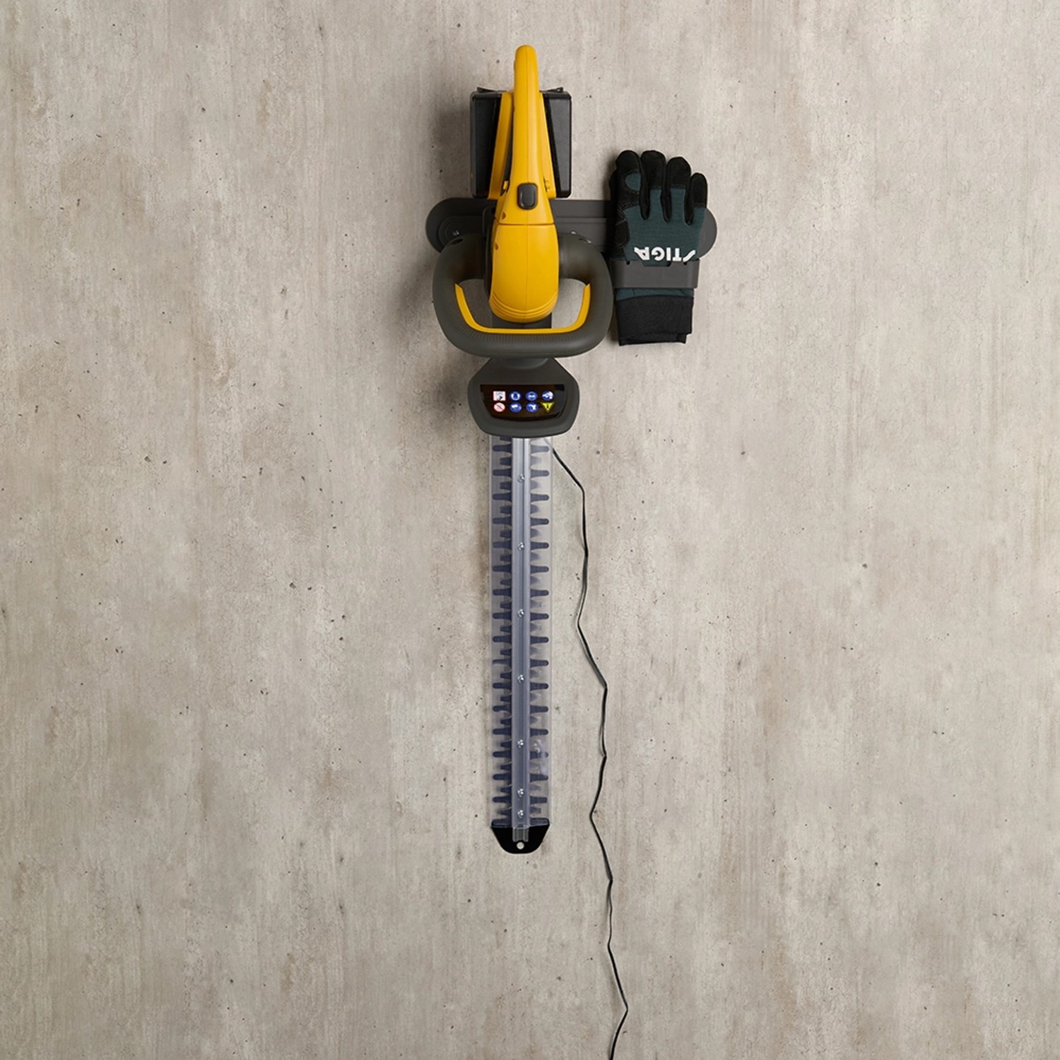 Set tagliasiepi a batteria Stiga HT 300e con batterie, caricabatterie e guanti su supporto a parete.