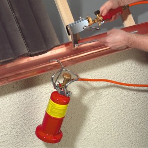 Cannello saldatore con cartuccia di gas che salda una grondaia. Accessorio per saldatrice.