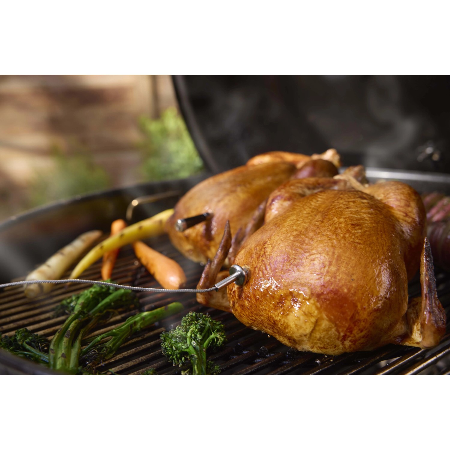 Tacchino grigliato con verdure su una griglia, monitorato con sonda di temperatura Weber Smart Hub.