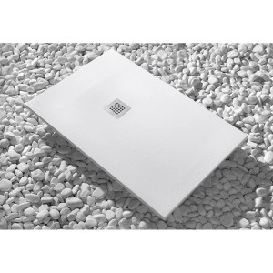 Piatto doccia bianco t.b.t. con scarico quadrato, circondato da ciottoli bianchi.
