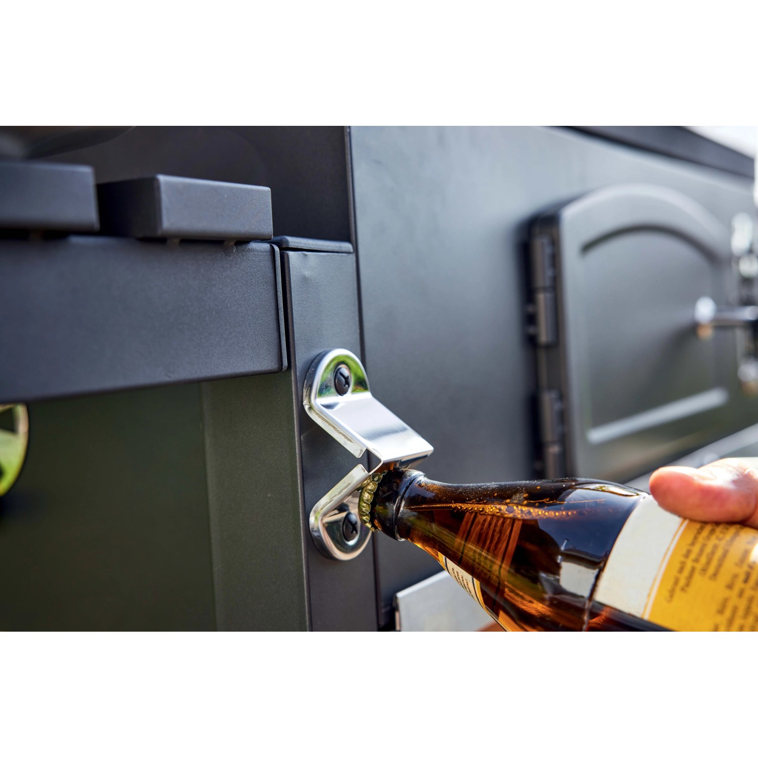 Apribottiglie sulla griglia a carbone t.b.t. che apre una bottiglia di birra.