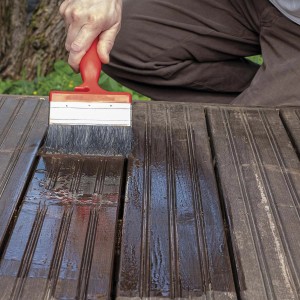 Applicazione di impregnante per legno con pennello su terrazza in legno.
