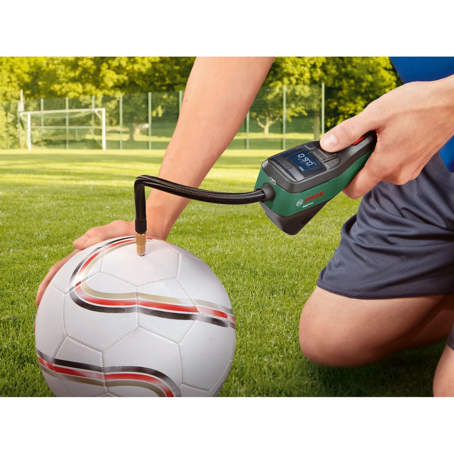 Pompa ad aria a batteria Bosch Easy Pump che gonfia un pallone su un campo di calcio.