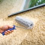 Mano che dipinge parete ruvida con rullo a dispersione LUX 25 cm. Rullo per pittura con manico blu.