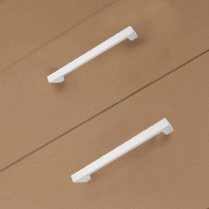 Maniglie per mobili bianche e moderne su una cassettiera in legno. Categoria: Maniglie e pomelli per mobili.