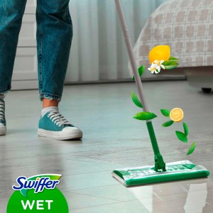 Swiffer lavapavimenti con panno umido in uso, limone e foglie fluttuanti nell'aria.