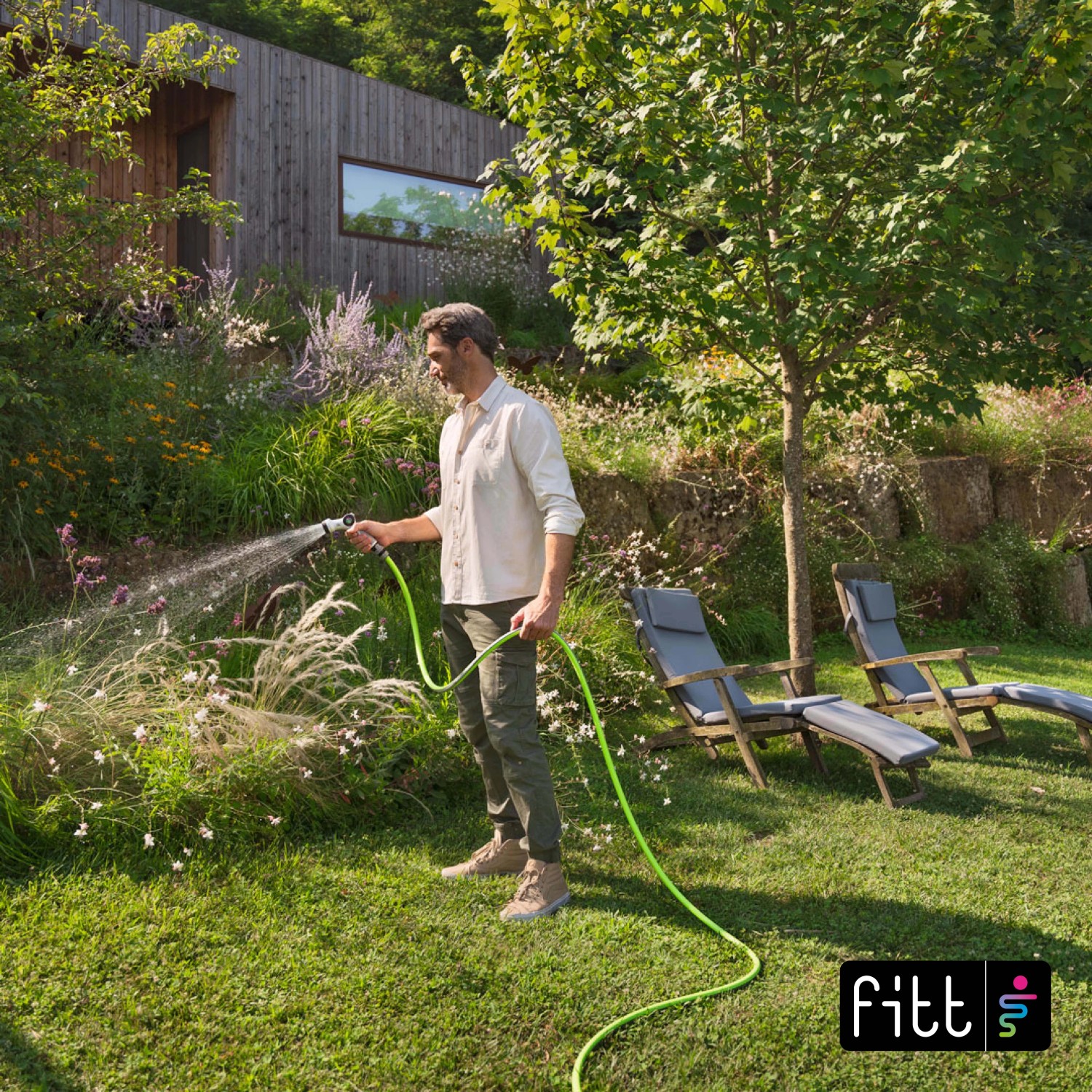 Uomo annaffia il giardino con tubo per irrigazione t.b.t.. Ideale per la cura del giardino.