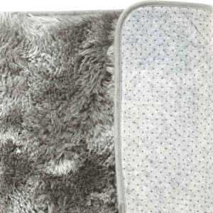 Dettaglio di un tappeto a pelo lungo grigio con fondo antiscivolo.