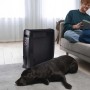 Stufa elettrica nera t.b.t. in soggiorno con coppia sul divano e cane sul tappeto.