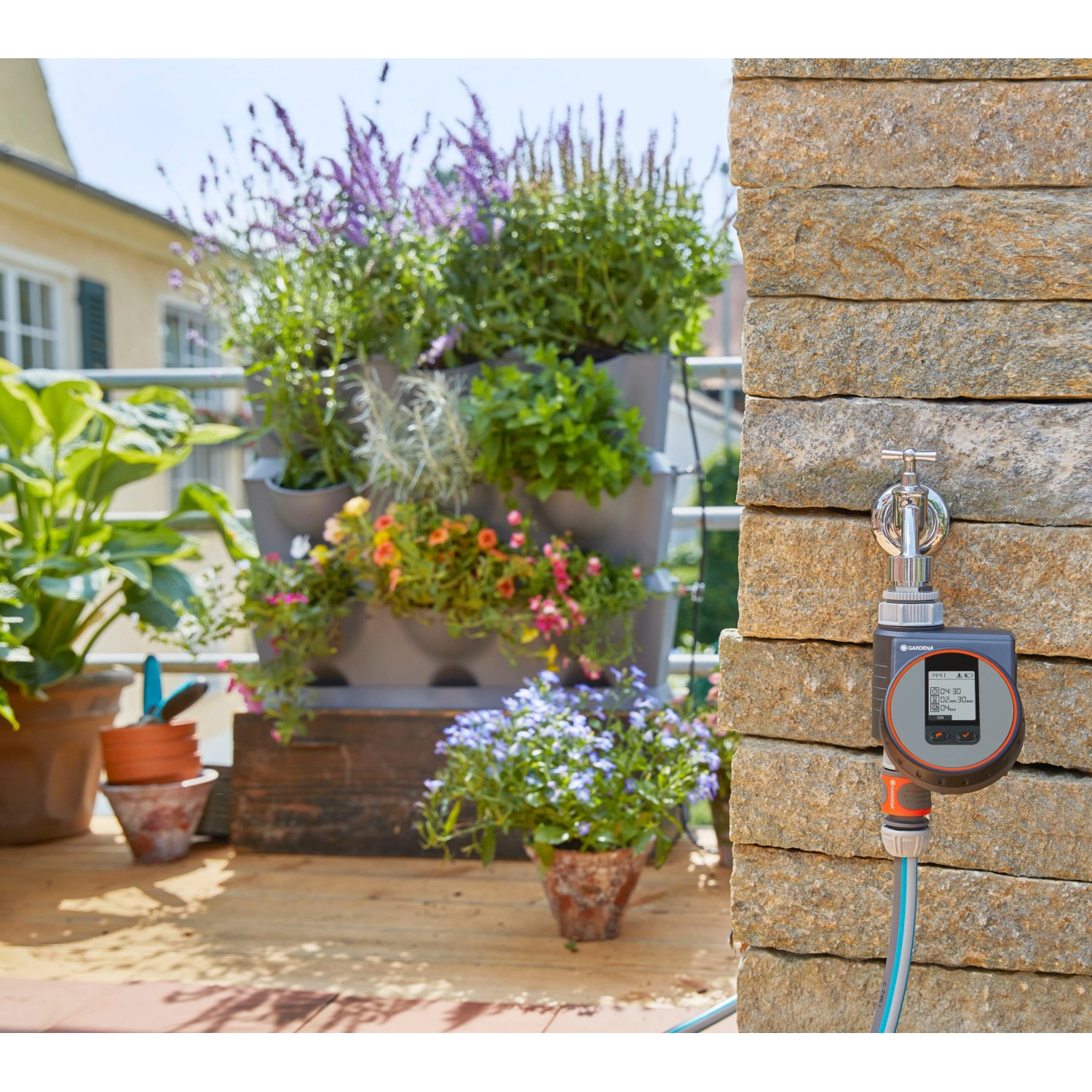 Irrigatore Gardena Flex collegato al rubinetto con balcone piantumato sullo sfondo.