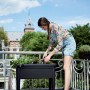 Tavolo di semina nero Elho Anzucht XXL Green Basics con donna che pianta sul balcone.