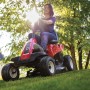 Tosaerba rider Troy-Bilt Mini-Rider 76T-S rosso con scarico laterale durante il taglio.