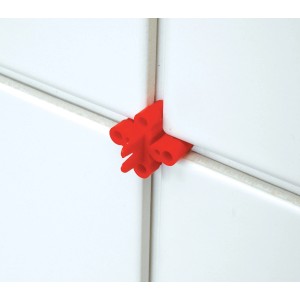 Distanziatore per piastrelle LUX rosso (6/7 mm) tra piastrelle bianche per fughe uniformi.