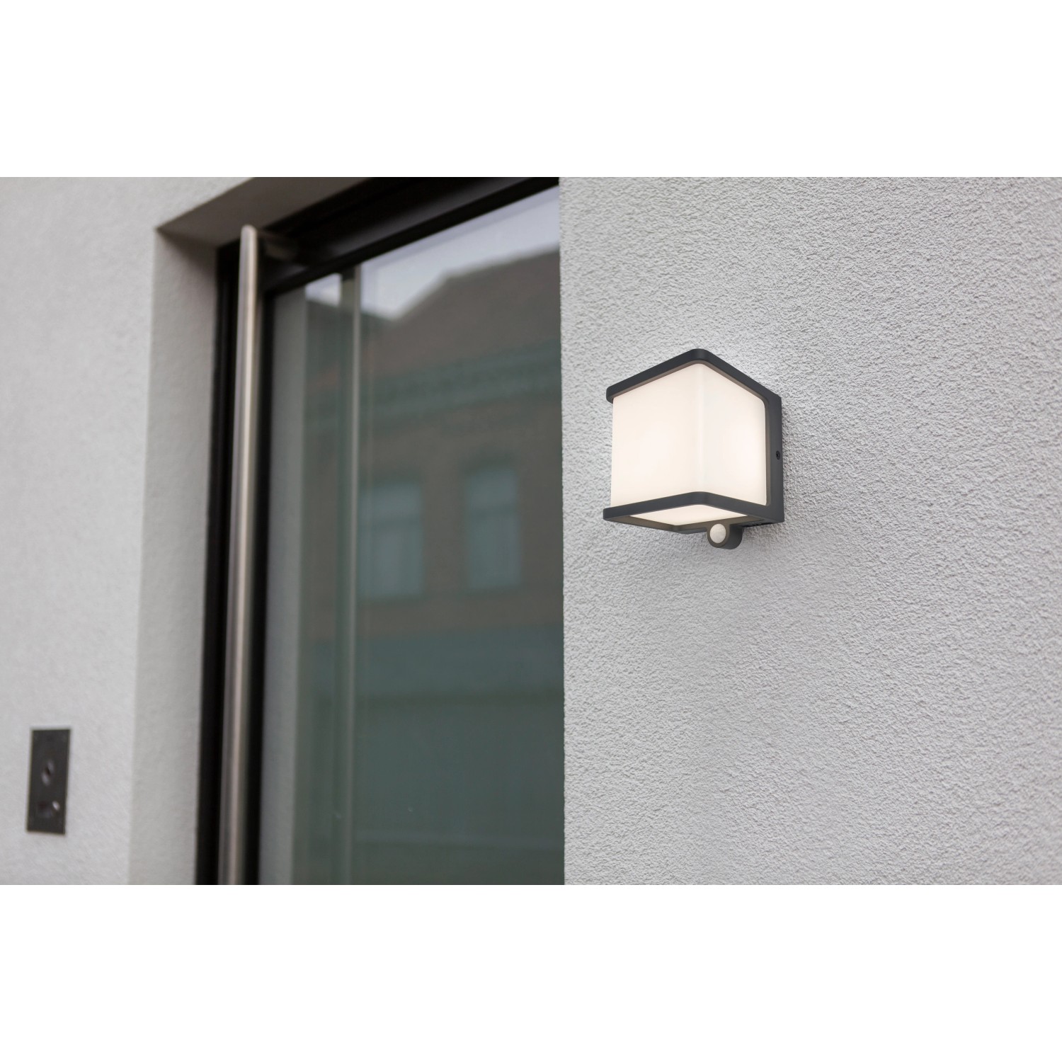 Lampada da parete solare a LED Lutec Doblo color antracite con sensore di movimento su muro bianco.