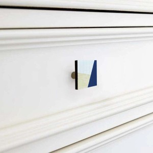 Pomello per mobili t.b.t. quadrato con motivo blu, beige e bianco su comò bianco.