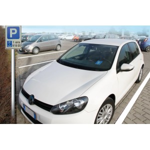 Auto bianca parcheggiata in un parcheggio con cartello. Accessori auto interni.