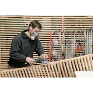 Uomo che leviga il legno con respiratore LUX P3. Filtro antiparticolato per lavorare in sicurezza.