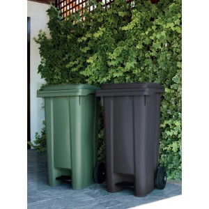 Due pattumiere t.b.t. verdi e antracite con coperchio e pedale davanti a una siepe verde.
