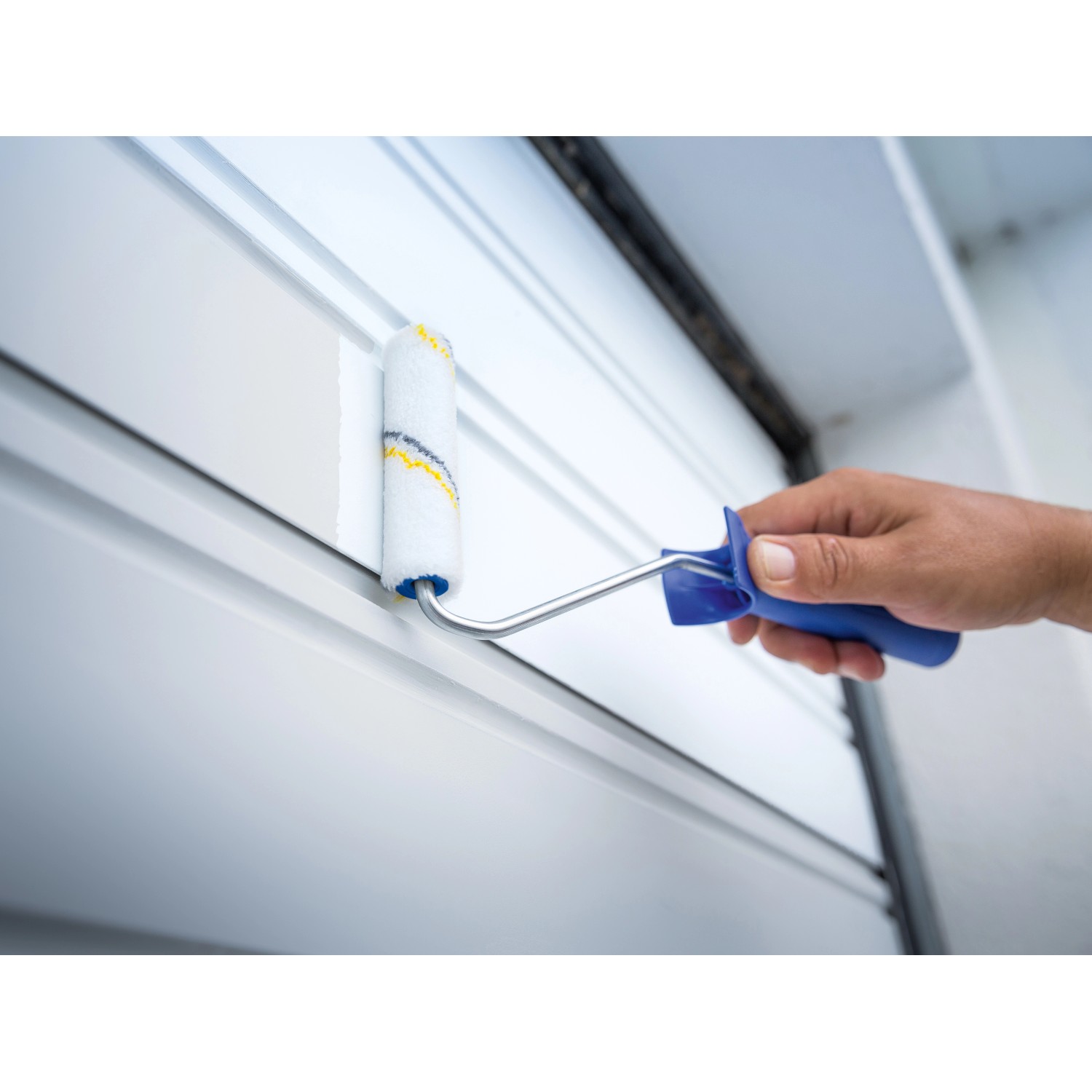 Rullo per vernice LUX (12 cm) in uso: mano che dipinge pannelli bianchi con rullo.