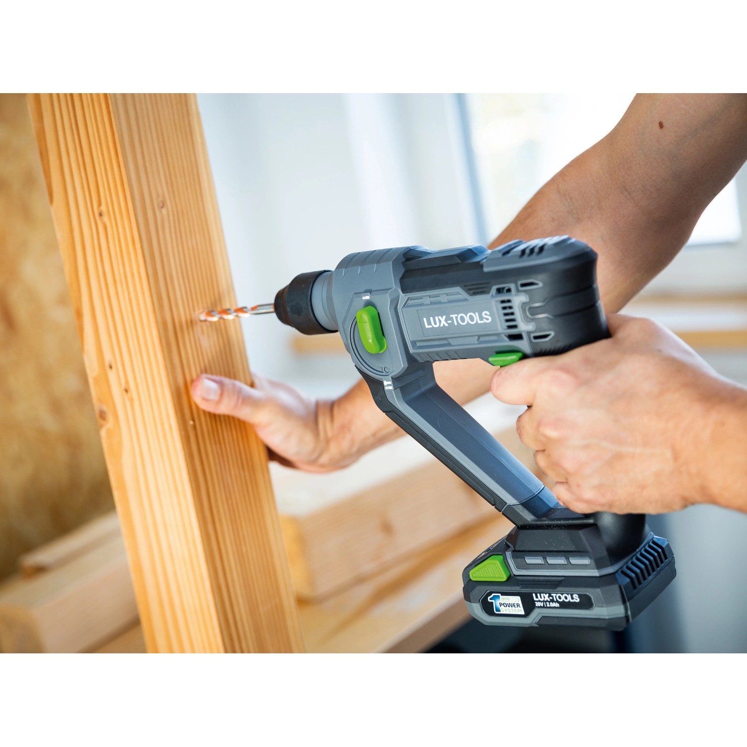 Trapano a percussione a batteria LUX A-BH-20 che fora il legno. Trapano a percussione a batteria con design grigio e verde.