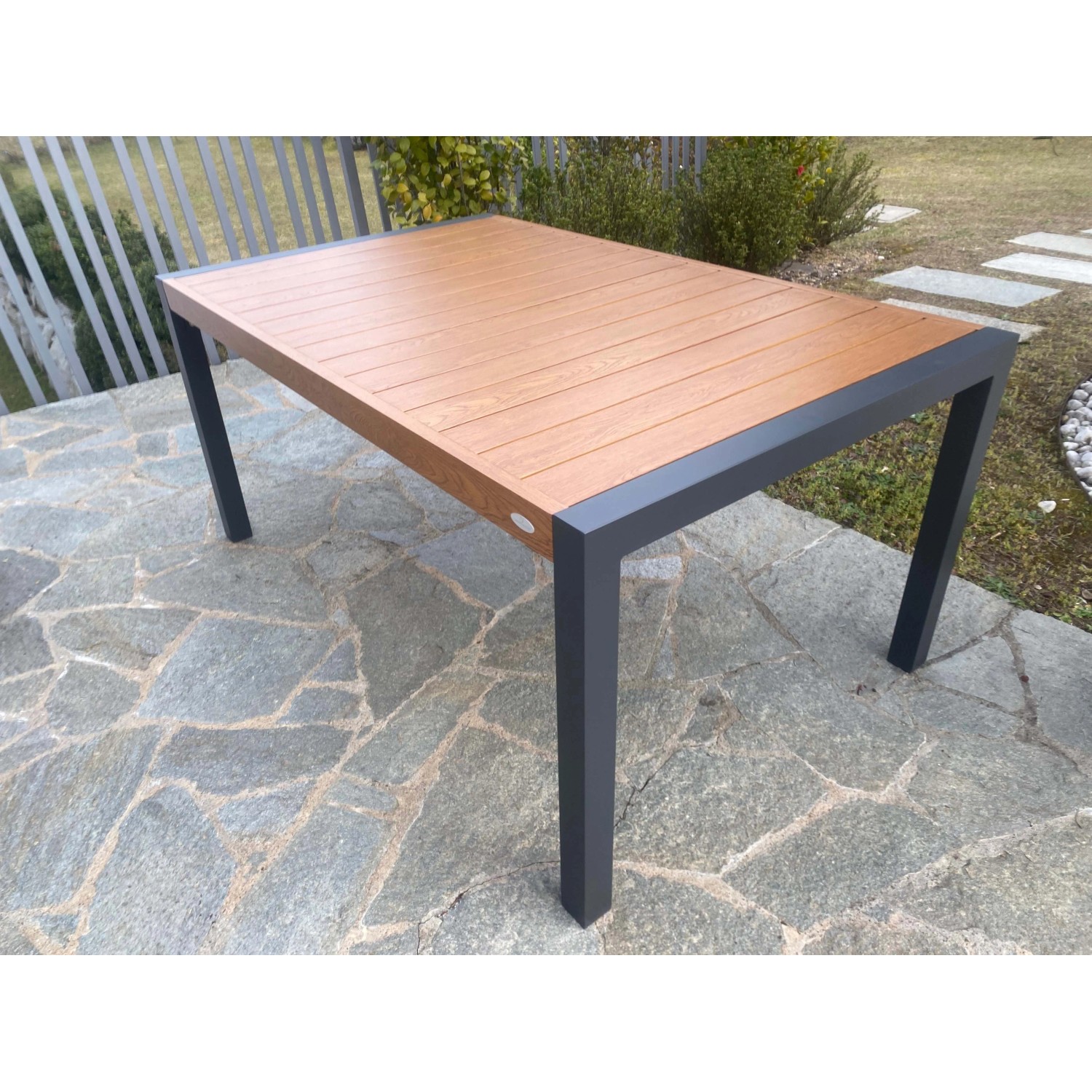 Tavolo da giardino rettangolare con piano effetto legno e struttura in metallo grigio.