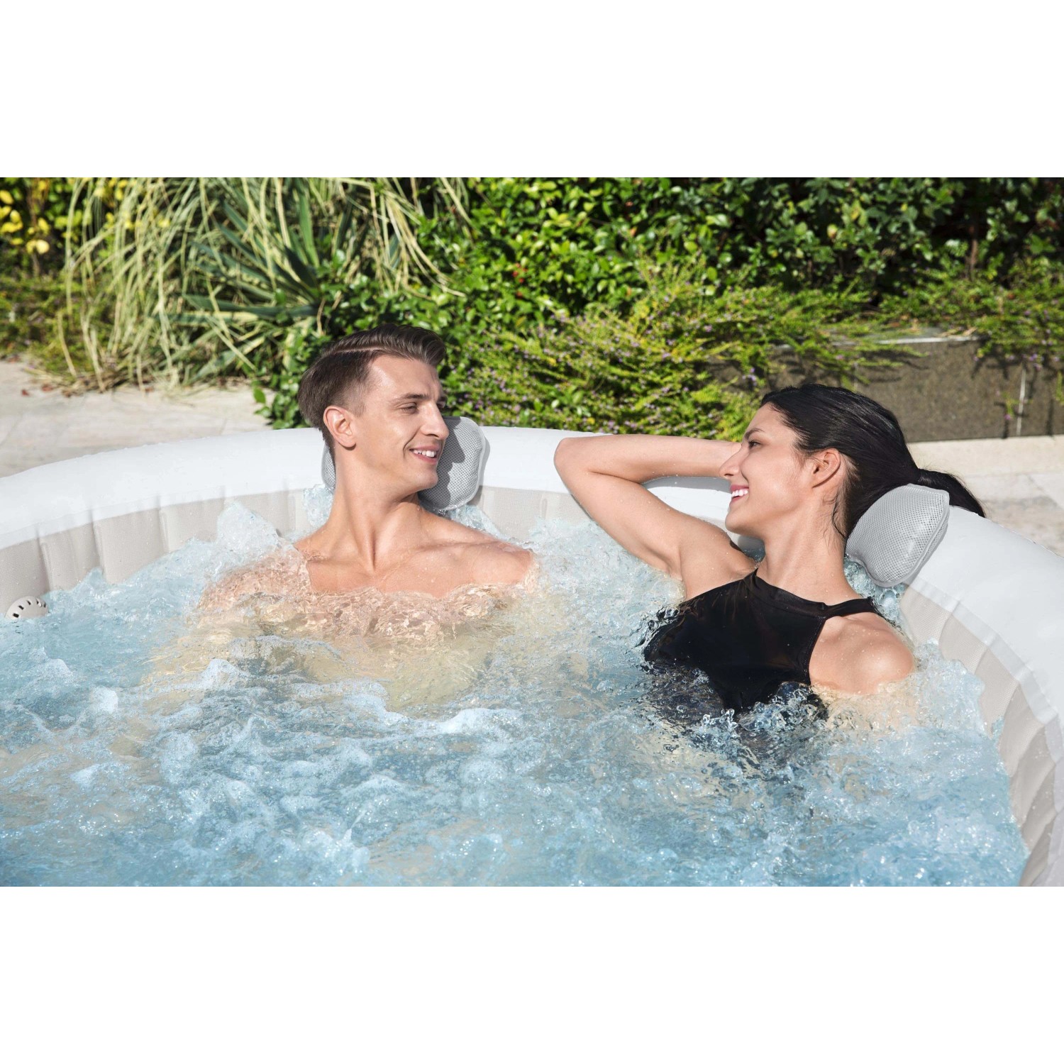 Coppia si rilassa nella vasca idromassaggio LAY-Z-SPA con cuscini poggiatesta imbottiti.