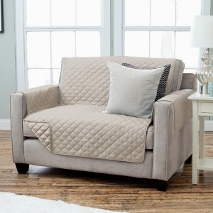 Copridivano trapuntato beige con braccioli e cuscini su un divano.