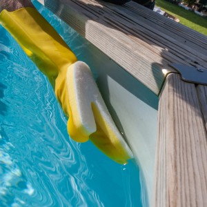 Guanto giallo Gre con spugna per la pulizia della piscina sulla linea di galleggiamento.