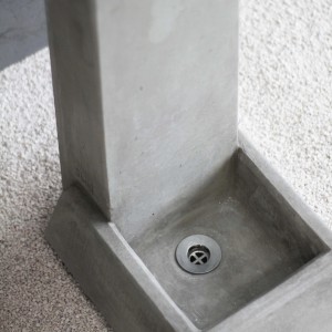 Dettaglio di una fontana da giardino in cemento grigio con scarico.