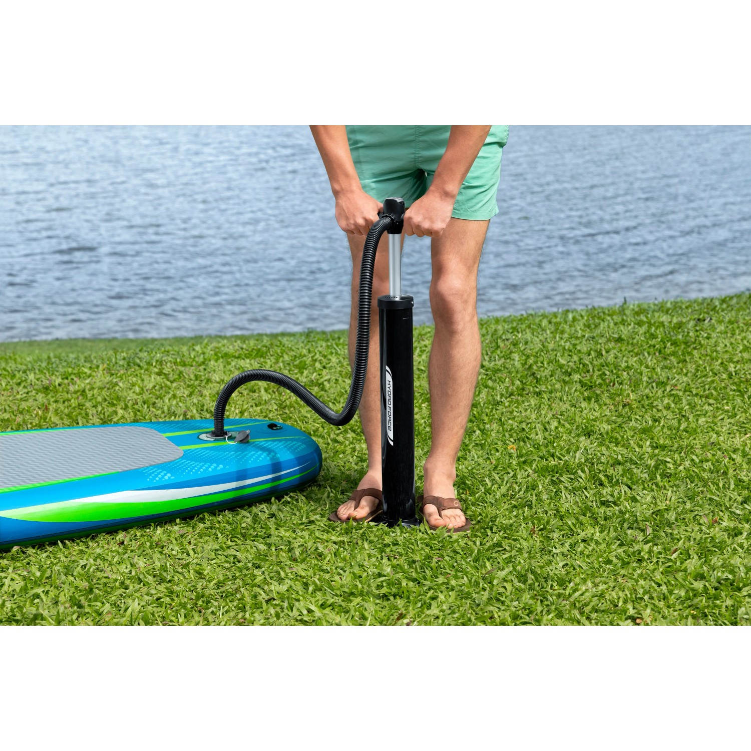 Gonfiaggio del Bestway SUP Aqua Journey con pompa. La tavola è blu-verde e si trova su un prato.