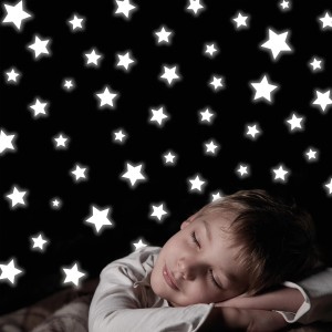 Bambino che dorme sotto adesivi murali a forma di stelle.