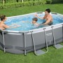 Piscina ovale con struttura metallica e famiglia in giardino. Piscina fuori terra.