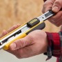 Cutter Stanley FatMax™ 18 mm, nero-giallo, tenuto in mano. Coltello con alimentatore di lame.